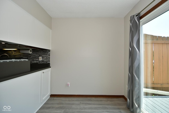 kitchen featuring light wood-type flooring, white cabinets, and backsplash