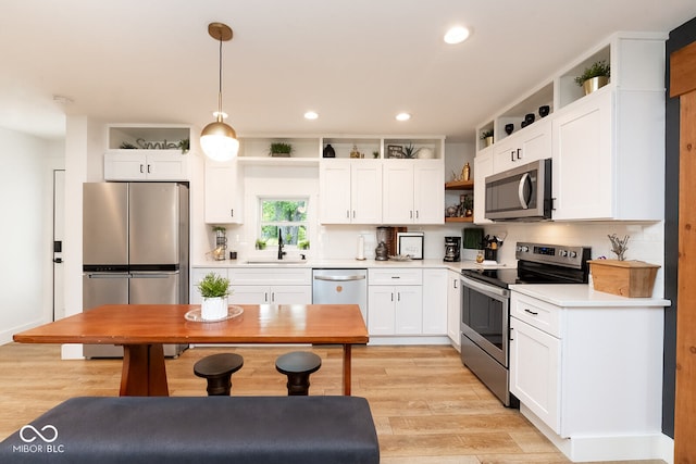 kitchen with white cabinetry, pendant lighting, appliances with stainless steel finishes, and light wood-type flooring