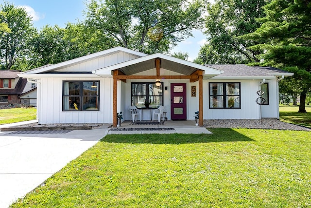 view of front of home featuring a porch, roof with shingles, a front yard, and board and batten siding