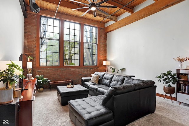 carpeted living room with brick wall, beamed ceiling, wooden ceiling, and ceiling fan