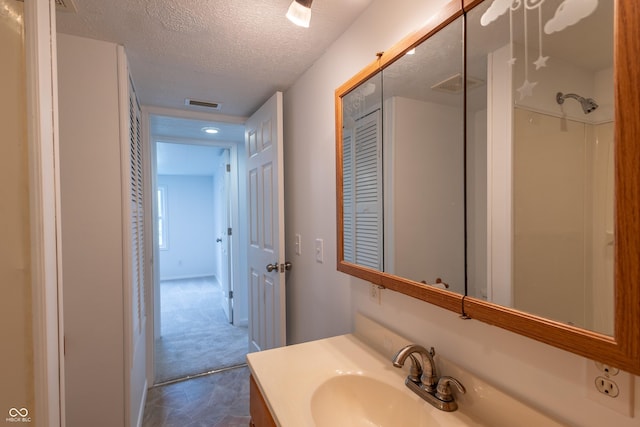 bathroom with a textured ceiling, vanity, and visible vents