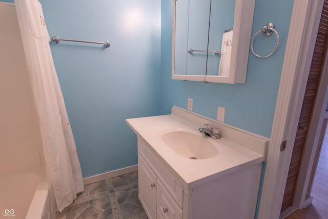 bathroom with curtained shower, vanity, and baseboards