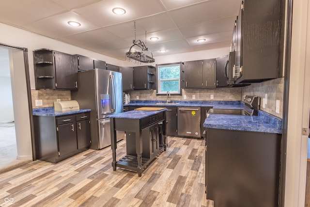 kitchen with dark countertops, stainless steel appliances, open shelves, and light wood-style flooring