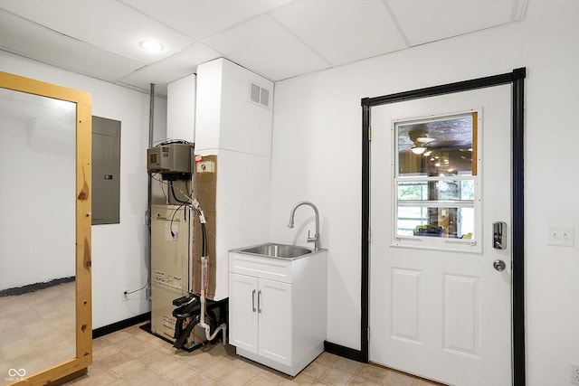 laundry area with light floors, a sink, cabinet space, and electric panel