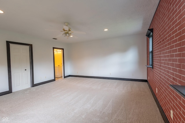 unfurnished room with recessed lighting, light colored carpet, a ceiling fan, brick wall, and baseboards