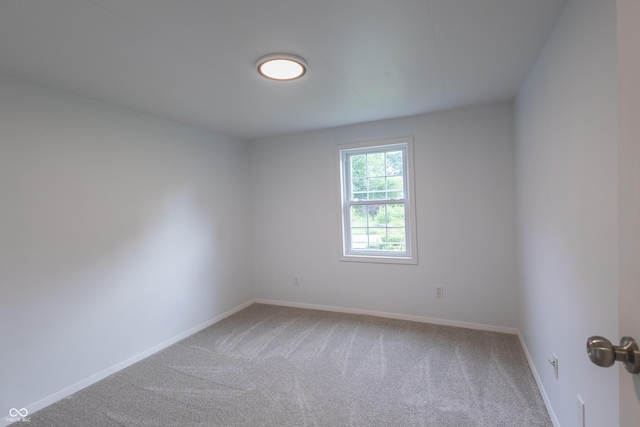 carpeted spare room featuring baseboards