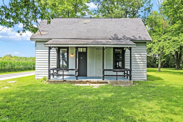 view of front of home featuring a front yard, covered porch, and roof with shingles