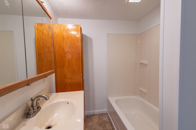 full bath featuring shower / washtub combination, a textured ceiling, baseboards, and vanity