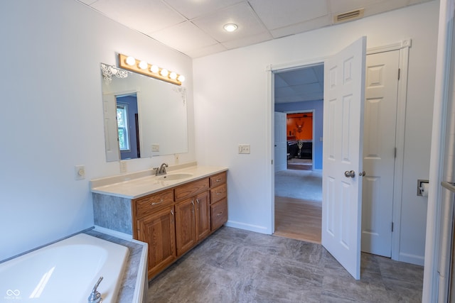 bathroom with visible vents, baseboards, a bathtub, vanity, and a paneled ceiling