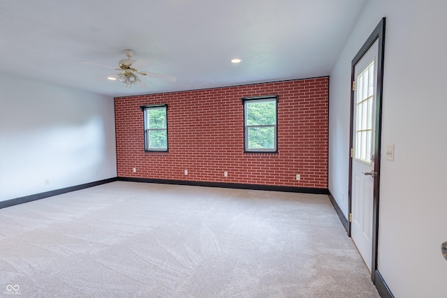 carpeted spare room featuring ceiling fan, brick wall, recessed lighting, and baseboards