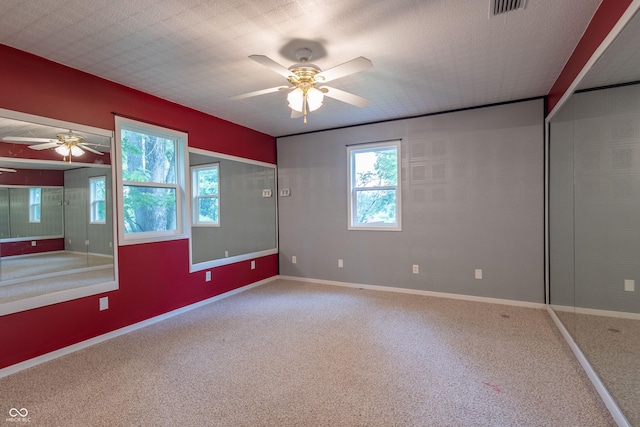 unfurnished room with carpet, visible vents, ceiling fan, a textured ceiling, and baseboards