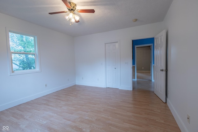 interior space with light wood finished floors, ceiling fan, baseboards, and a textured ceiling