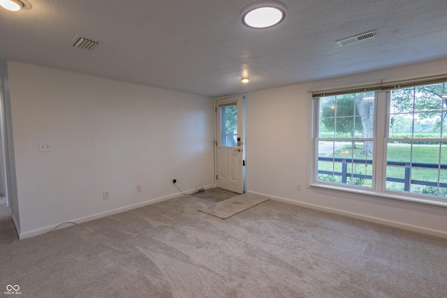 interior space with carpet floors, visible vents, a textured ceiling, and baseboards