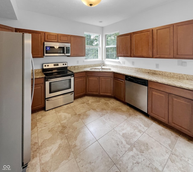 kitchen with appliances with stainless steel finishes, light stone counters, and sink