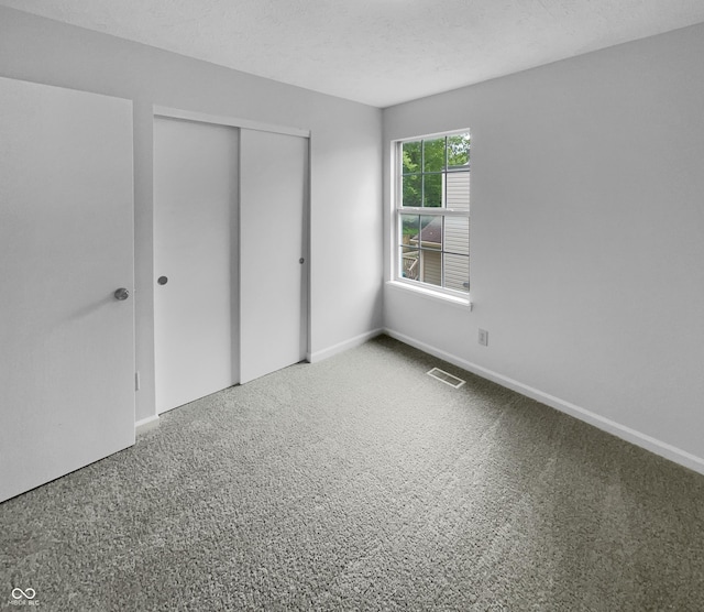 unfurnished bedroom featuring a textured ceiling, a closet, and carpet