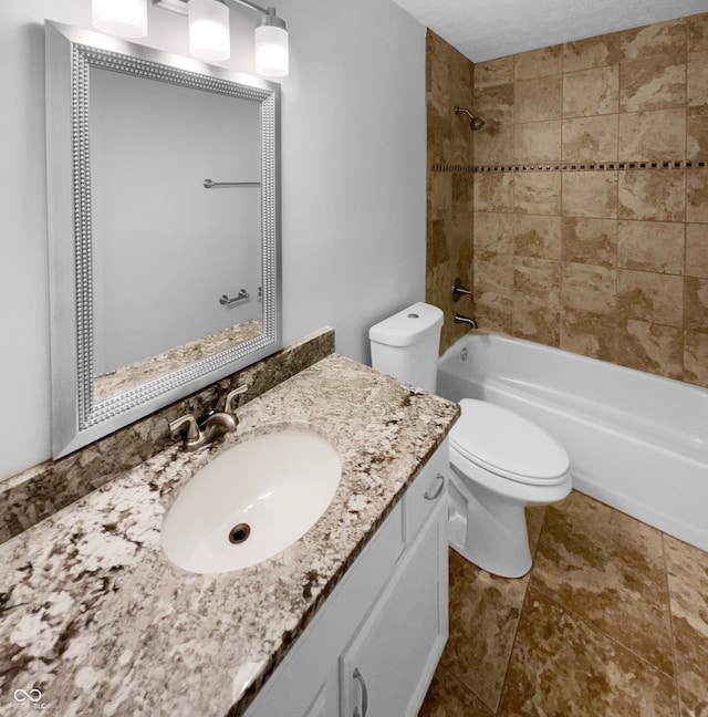 full bathroom with toilet, vanity, a textured ceiling, and tiled shower / bath