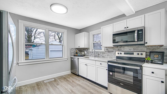 kitchen with white cabinetry, sink, stainless steel appliances, and a textured ceiling