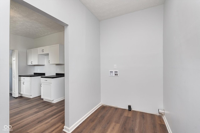 laundry area with washer hookup, dark wood-type flooring, a textured ceiling, and cabinets