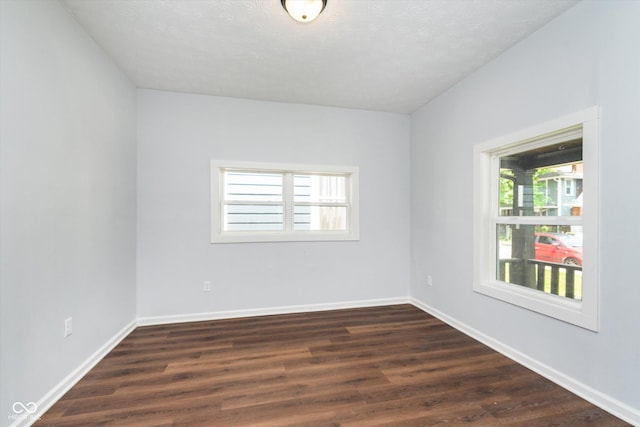 empty room with dark hardwood / wood-style flooring and a textured ceiling