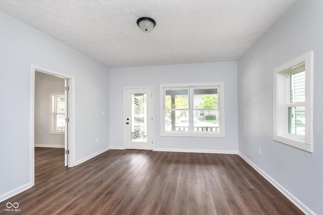 unfurnished room with a textured ceiling and dark hardwood / wood-style flooring