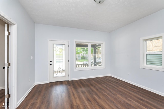 spare room featuring a textured ceiling and dark hardwood / wood-style flooring