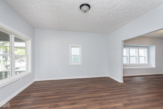 spare room with a textured ceiling and dark hardwood / wood-style flooring