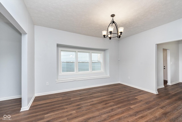 unfurnished room with a textured ceiling, an inviting chandelier, and dark hardwood / wood-style floors