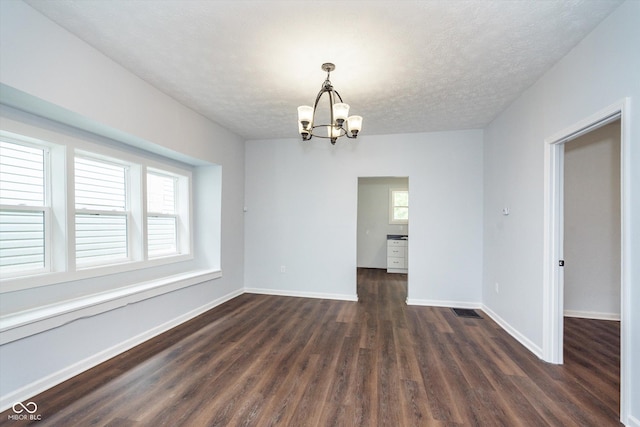 unfurnished dining area featuring dark wood-type flooring, an inviting chandelier, and a textured ceiling