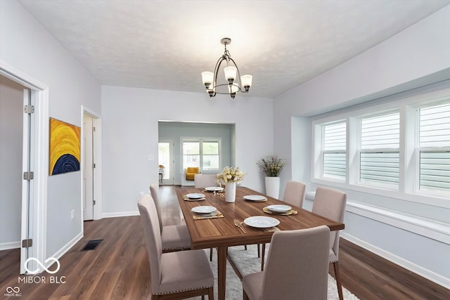 dining area with a chandelier, dark wood-type flooring, visible vents, and baseboards