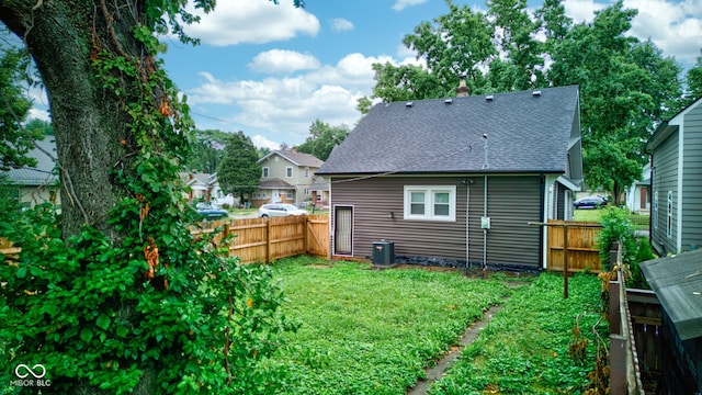 back of property featuring central AC unit and a yard