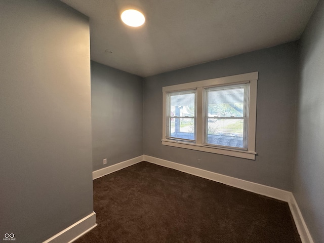 spare room with dark colored carpet