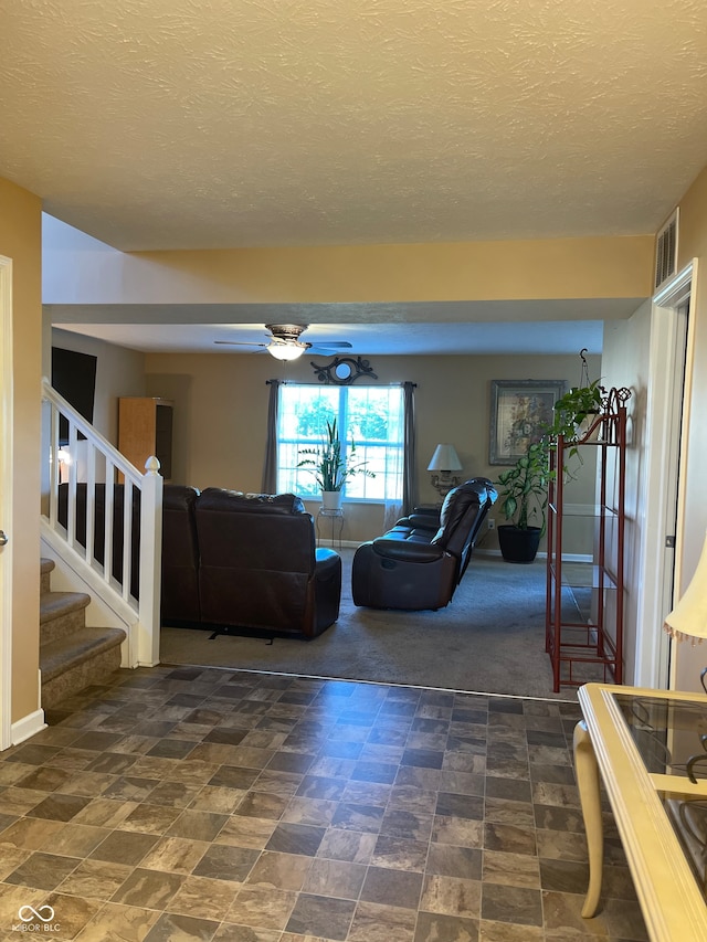 living room featuring dark carpet, a textured ceiling, and ceiling fan