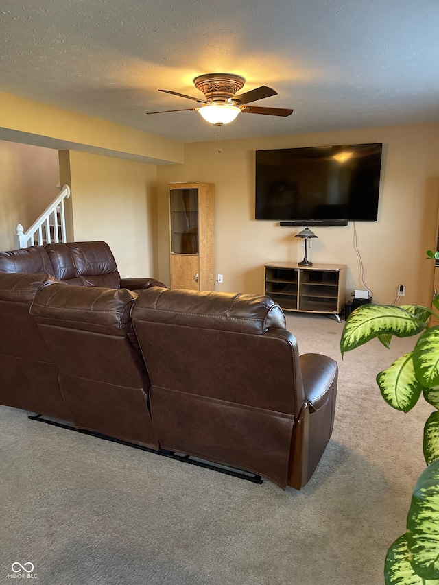 living room with a textured ceiling, ceiling fan, and carpet flooring