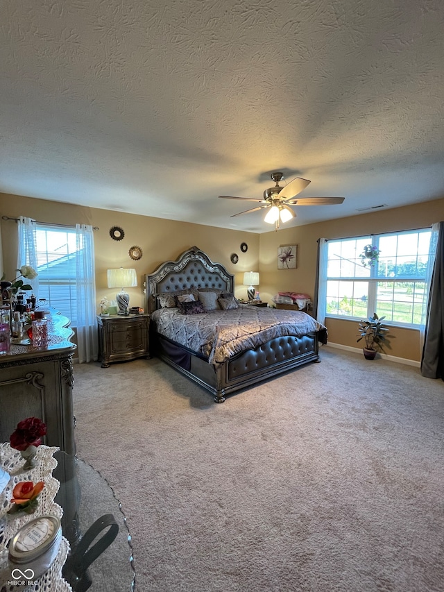 bedroom featuring a textured ceiling, ceiling fan, and light colored carpet