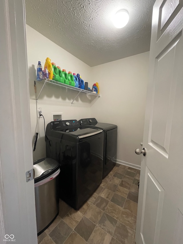 laundry area with separate washer and dryer, dark tile patterned flooring, and a textured ceiling