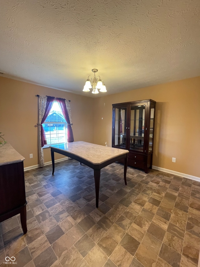 recreation room with a textured ceiling, dark tile patterned flooring, and a chandelier