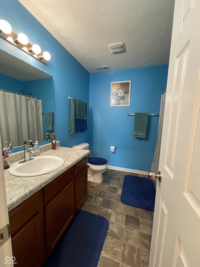 bathroom featuring tile patterned floors, toilet, vanity, and a textured ceiling