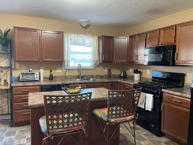 kitchen with black appliances, sink, a kitchen island, a textured ceiling, and light tile patterned floors