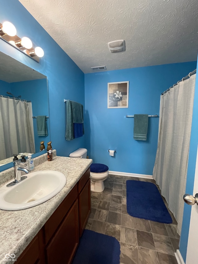 bathroom with tile patterned floors, toilet, vanity, and a textured ceiling