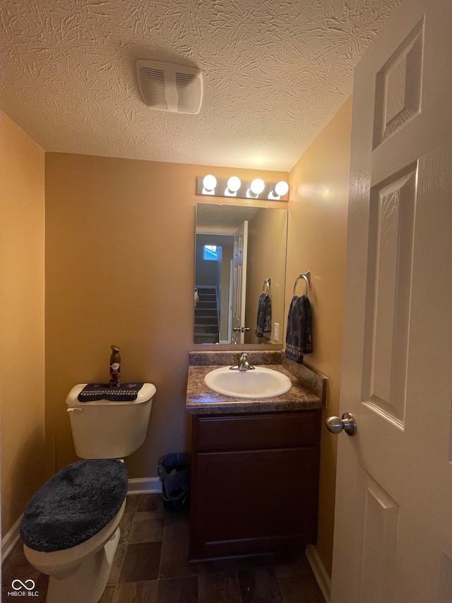 bathroom featuring vanity, a textured ceiling, and toilet