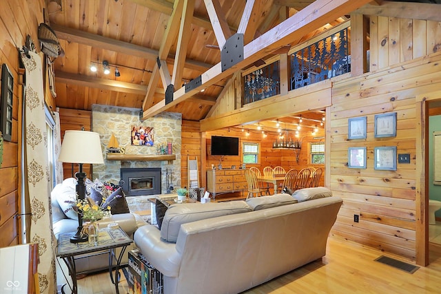 living room with wood walls, beam ceiling, and light wood-type flooring