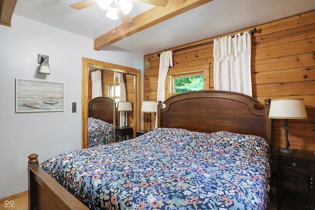 bedroom featuring wooden walls, beamed ceiling, a closet, and ceiling fan