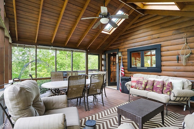 living room with rustic walls, a skylight, beam ceiling, ceiling fan, and wood-type flooring