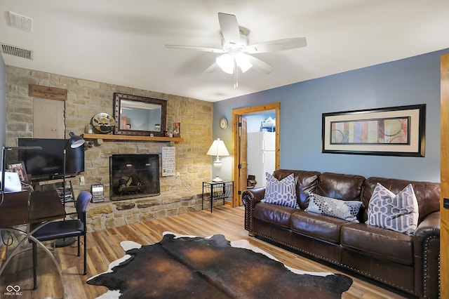 living room featuring a stone fireplace, ceiling fan, and hardwood / wood-style flooring