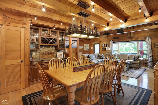 dining room with wood walls, light hardwood / wood-style flooring, beamed ceiling, and wood ceiling