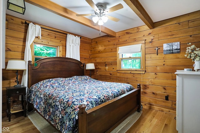 bedroom featuring wood walls, beam ceiling, ceiling fan, and hardwood / wood-style floors