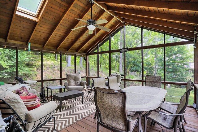 sunroom / solarium featuring ceiling fan, a healthy amount of sunlight, wood ceiling, and vaulted ceiling with skylight