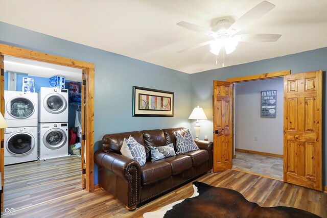 living room with stacked washer / dryer, hardwood / wood-style floors, and ceiling fan