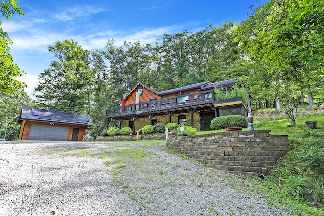 log home with a deck, a garage, and an outbuilding