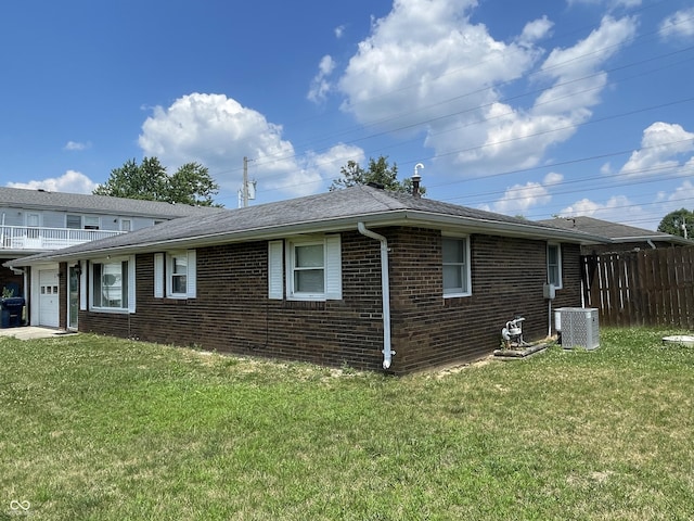 view of side of property with a yard, a garage, and central AC unit